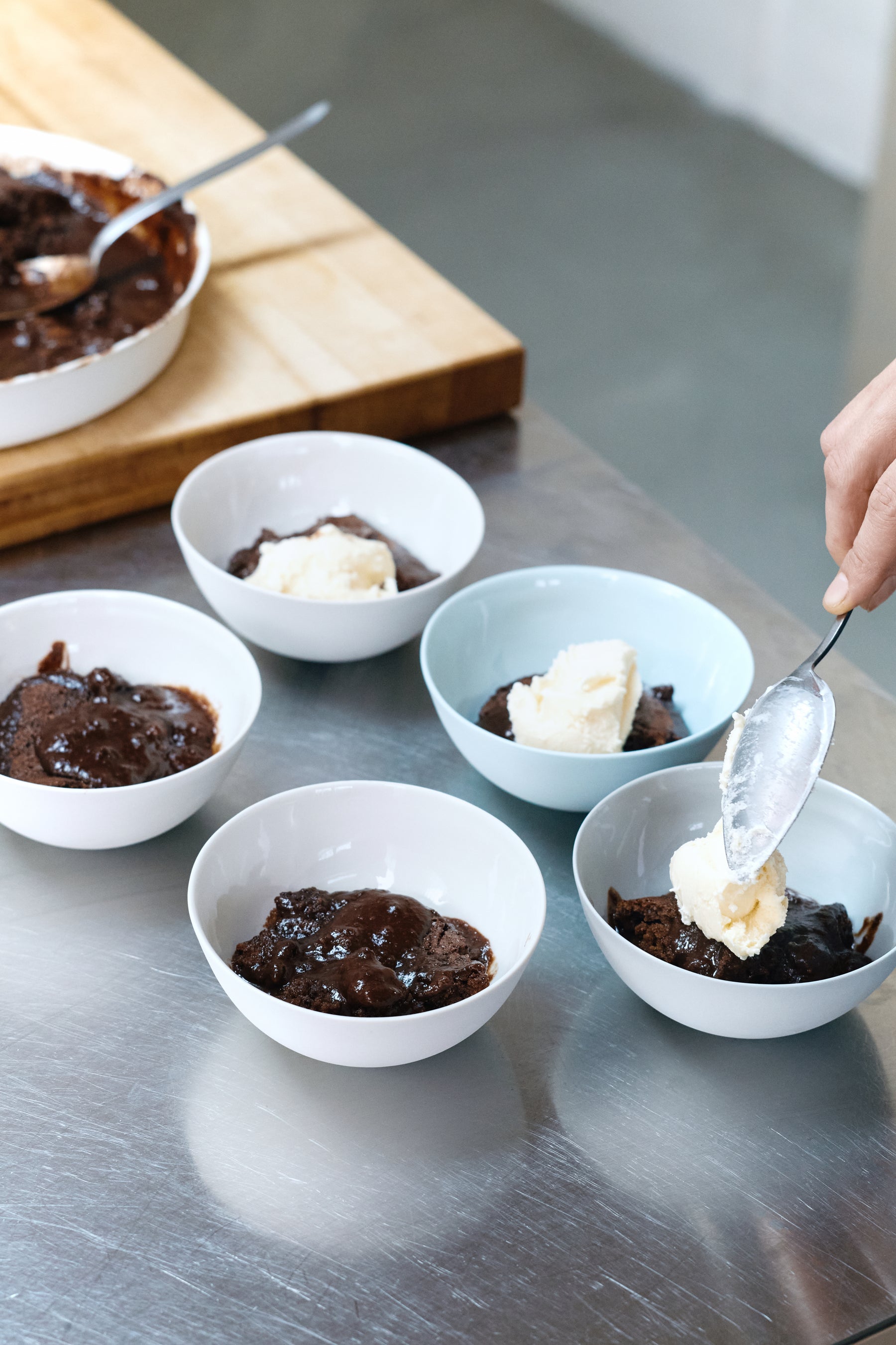 Chocolate and almond self-saucing pudding served in bowls with vanilla ice cream