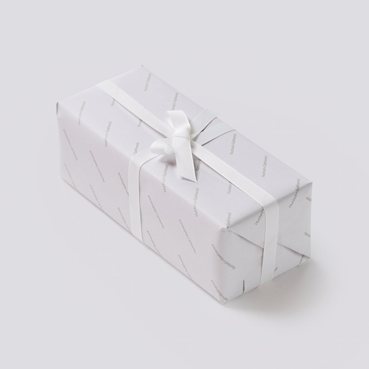 Hunted+Gathered gift box wrapped in branded paper with a white ribbon